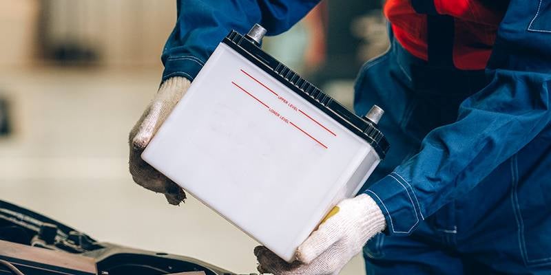 James Wood Motors Decatur in Decatur TX technician placing a new battery in an engine
