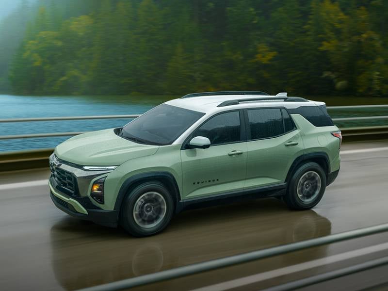James Wood Motors Decatur in Decatur TX mint green Chevrolet driving over a bridge in the rain
