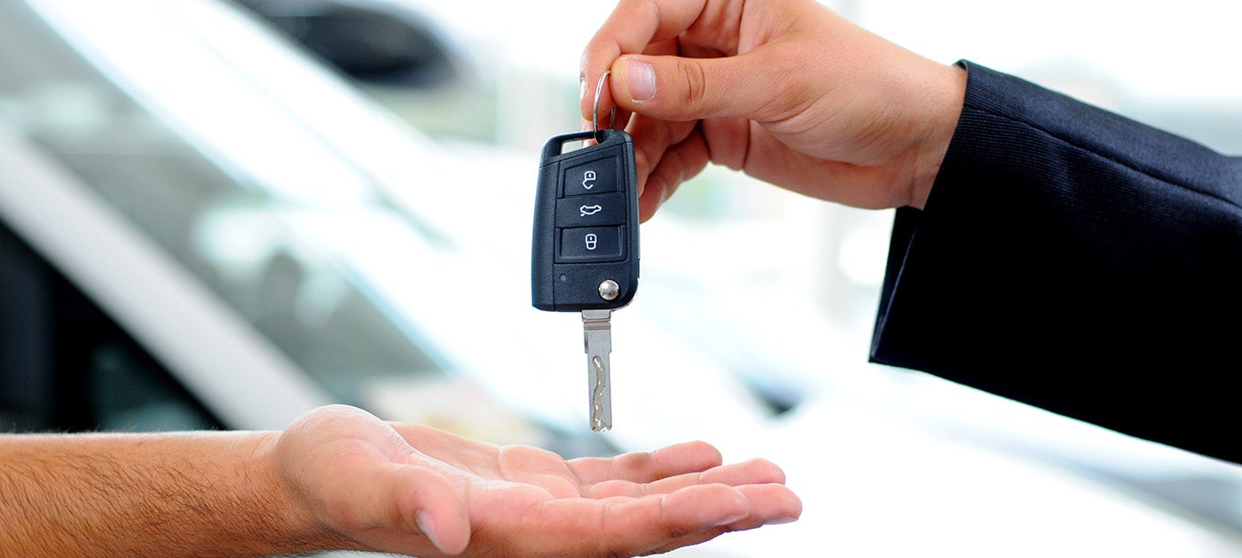 Car salesman passing key
