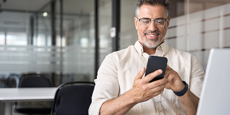 A gentleman sitting on his desk while on his phone